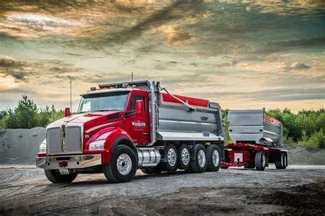 Red semi-trailer truck on a dirt road.