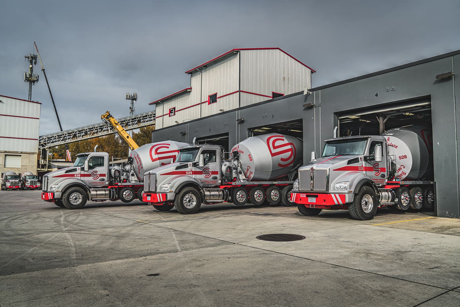 Three concrete mixer trucks in a garage.